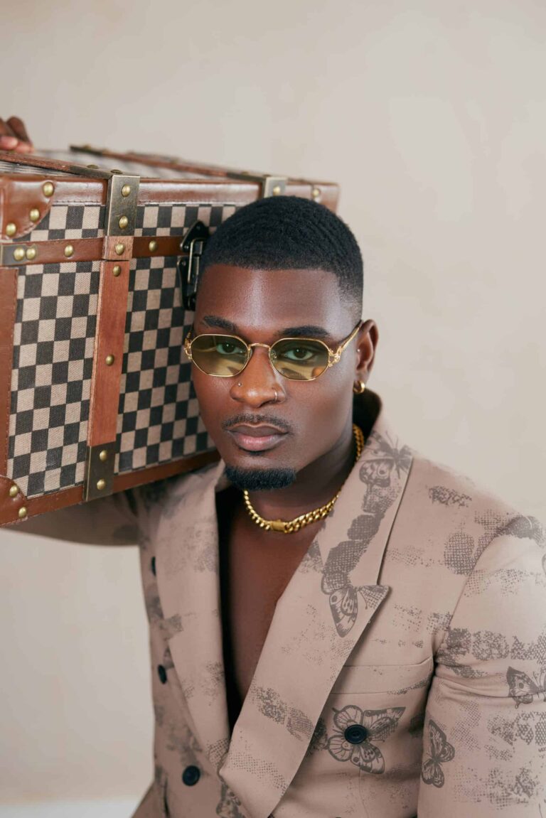 Man in sunglasses posing with checked luggage for a product and fashion shoot