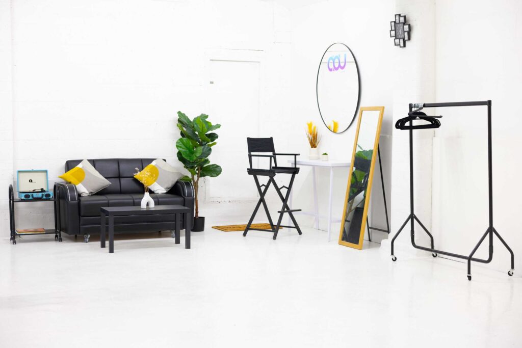 Bright white photography studio with seating, makeup station and clothing rail
